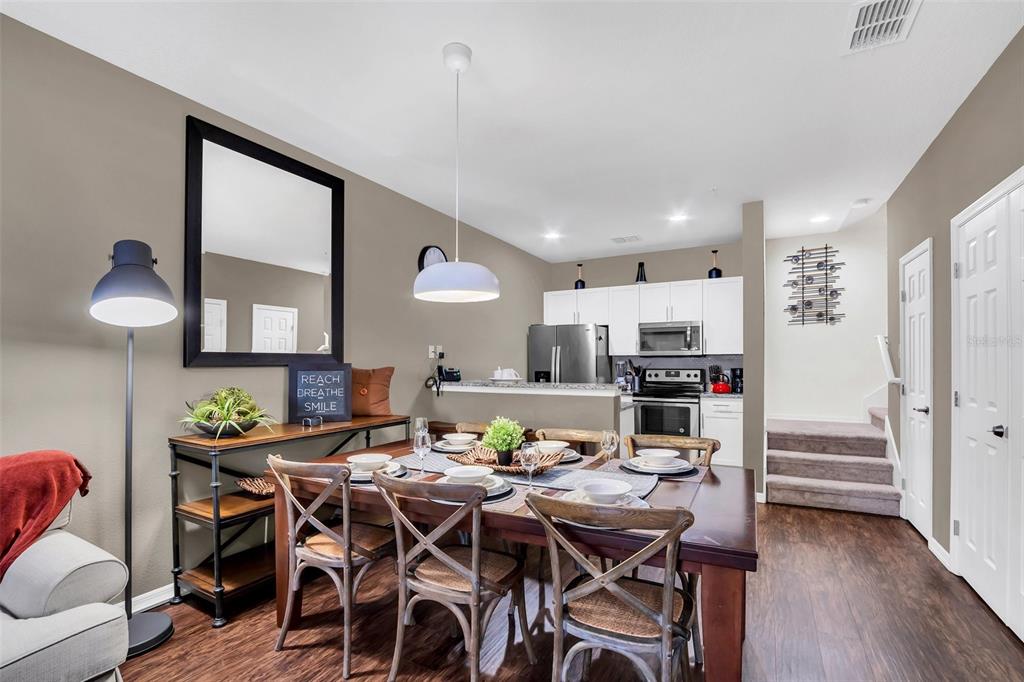 A dining area with a wooden table and chairs sits adjacent to an open kitchen — 8932 SHINE DRIVE, KISSIMMEE, FL
