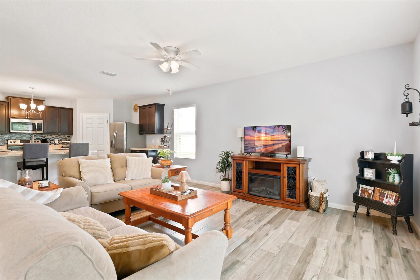 A living room with light wood-look flooring, a beige sofa, and a wooden media console — 2096 SW Leafy Road, FL 34953, FL
