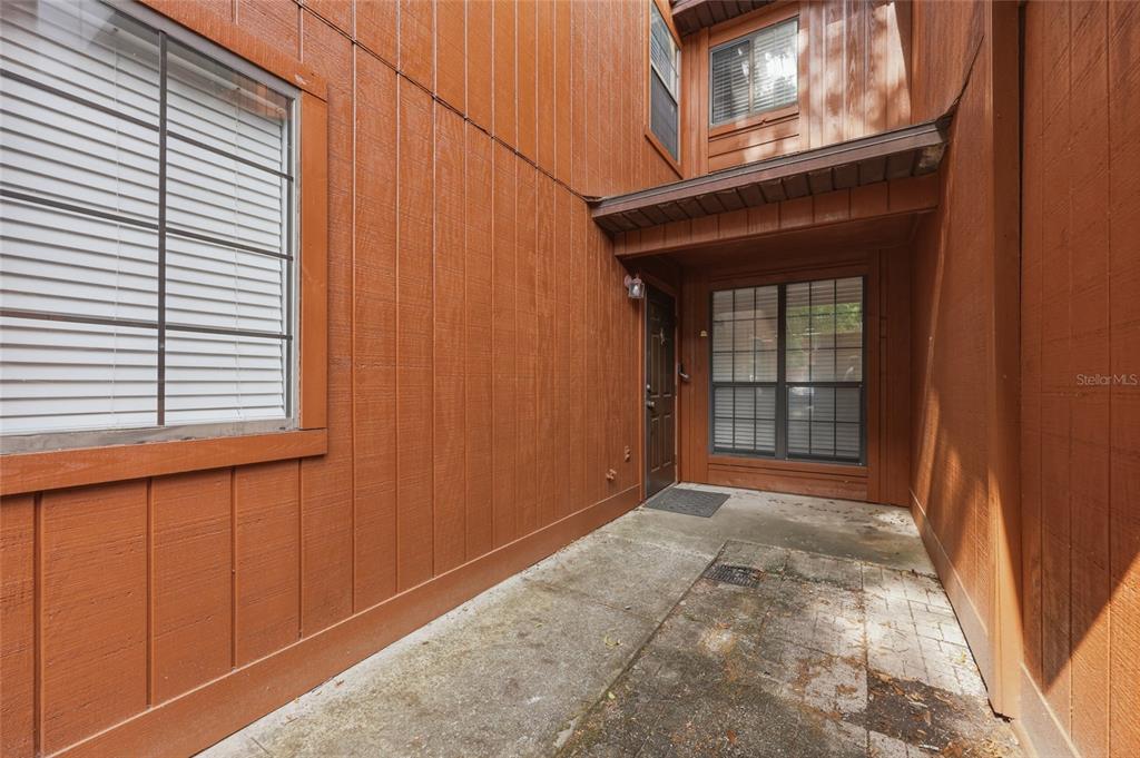 A concrete entryway leads to a brown front door flanked by windows on a building — 852 SW 58TH TERRACE, GAINESVILLE, FL