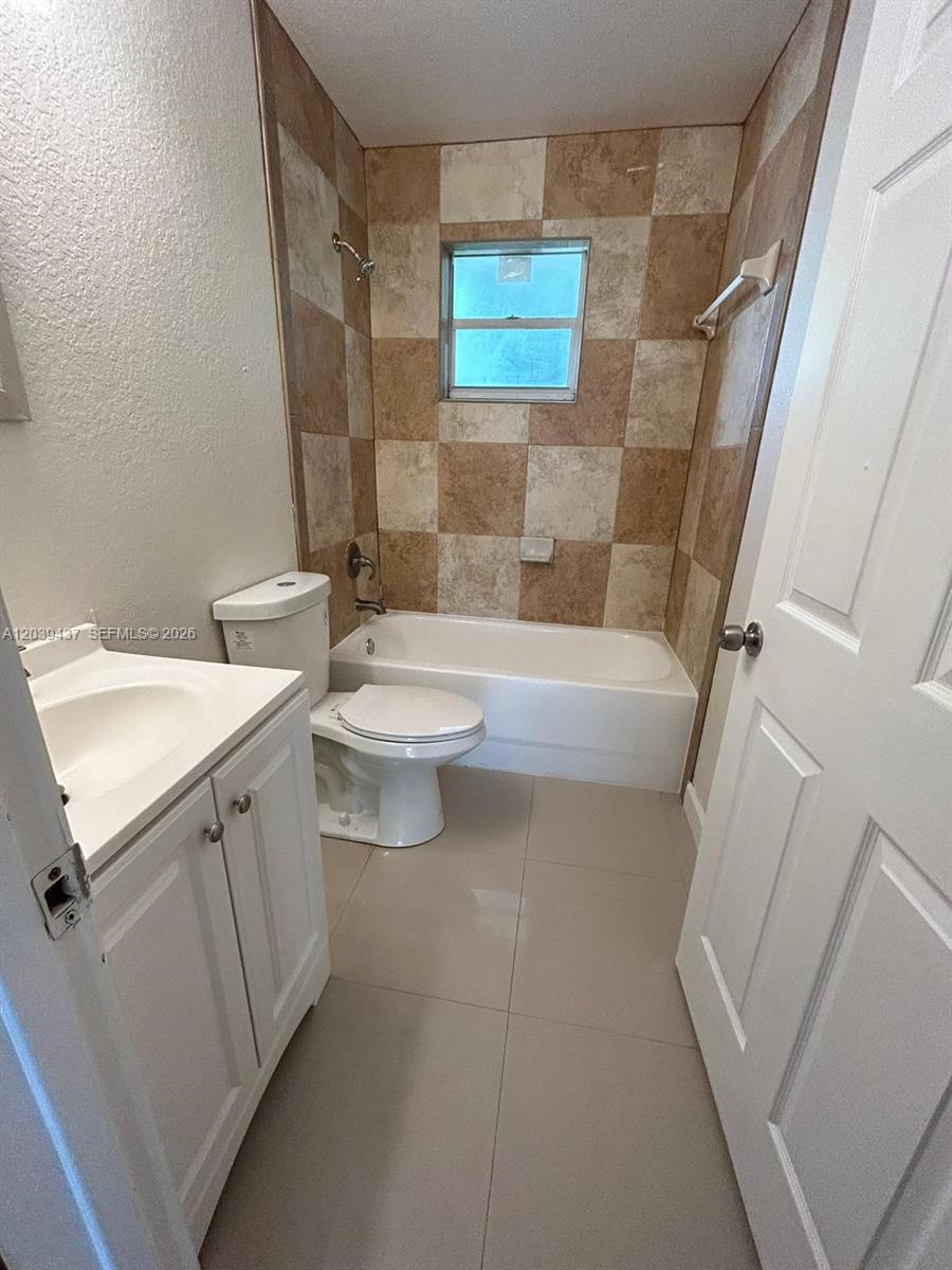 A bathroom features a white vanity, a toilet, and a bathtub with checkered tile walls — 1255 NW 55th Ter # 1257, Miami FL 33142, MIAMI, FL