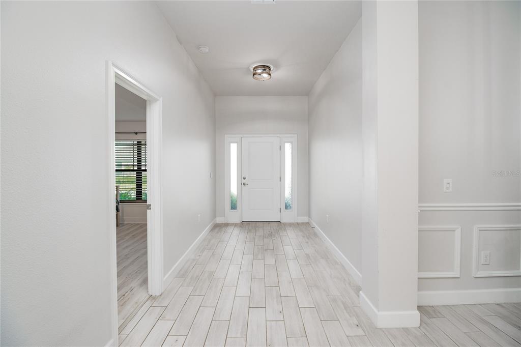 A bright entryway features light wood-look tile flooring, white walls, and a front door — 4820 SUMMIT VIEW WAY, AUBURNDALE, FL