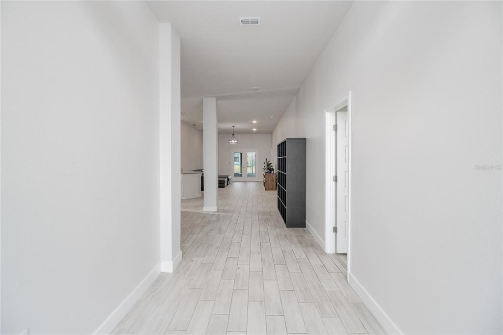 A long hallway with light wood-look tile floors leads toward an open living area — 4820 SUMMIT VIEW WAY, AUBURNDALE, FL