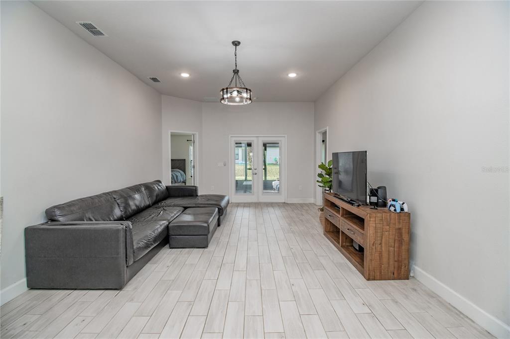 A living room features a gray sectional sofa, a wooden media console, and tile flooring — 4820 SUMMIT VIEW WAY, AUBURNDALE, FL