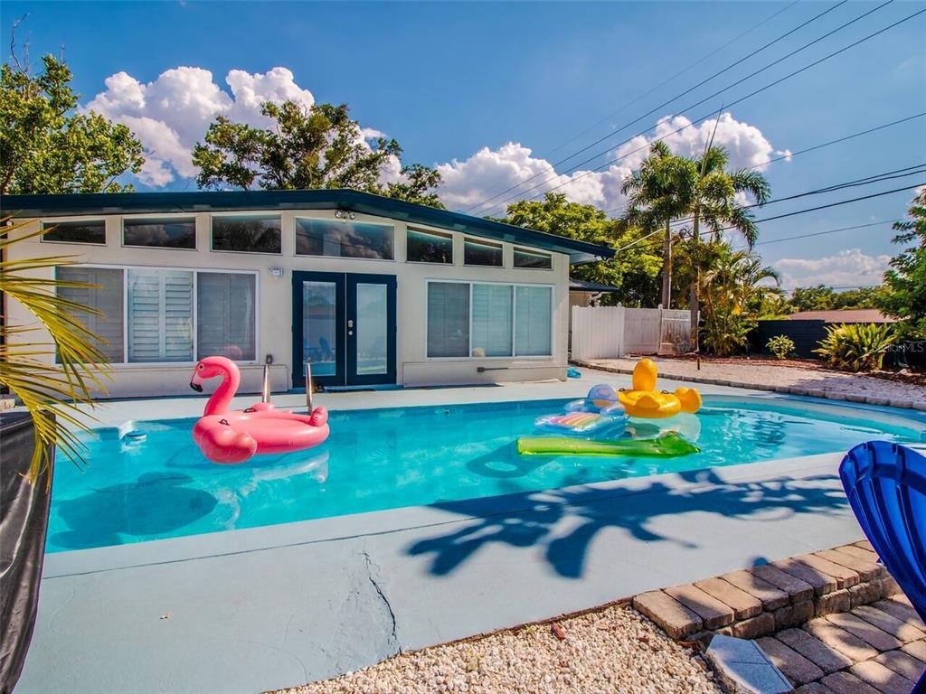 A swimming pool with inflatable floats sits in front of a house with large windows — 4401 LENMORE STREET UNIT 3, ORLANDO, FL