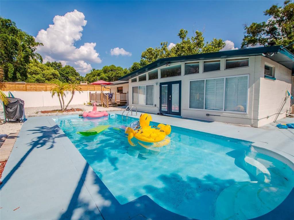 A swimming pool with yellow and pink inflatables sits in front of a white house — 4401 LENMORE STREET UNIT 3, ORLANDO, FL
