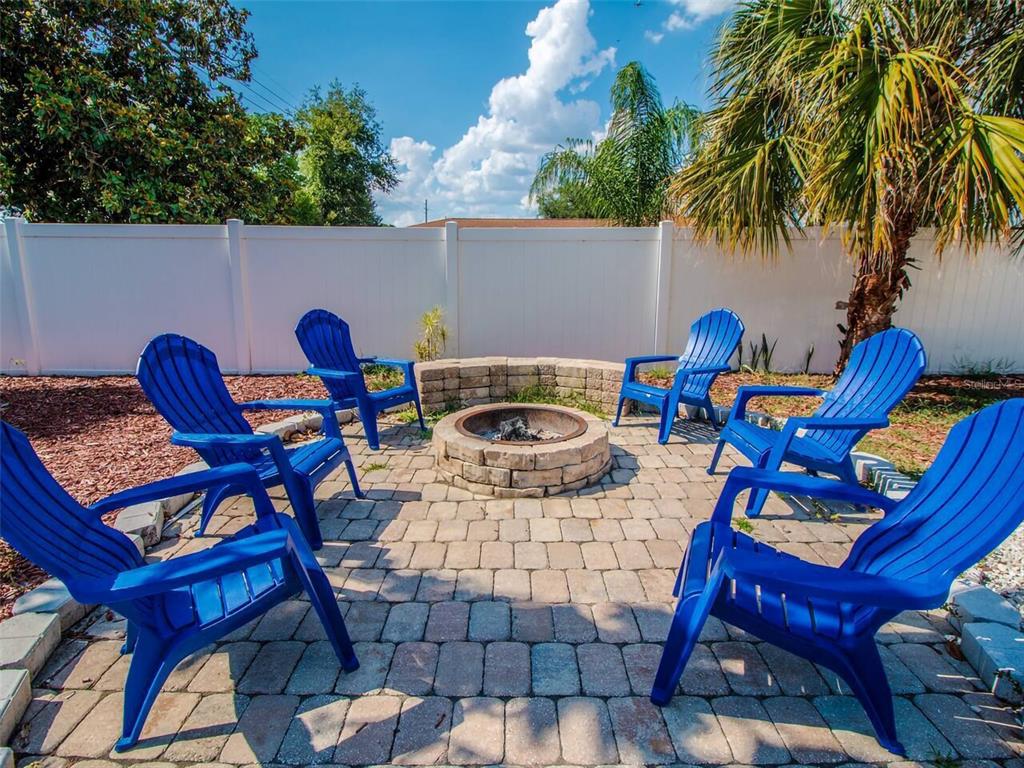 A backyard patio features a circular stone fire pit surrounded by six blue Adirondack chairs — 4401 LENMORE STREET UNIT 3, ORLANDO, FL