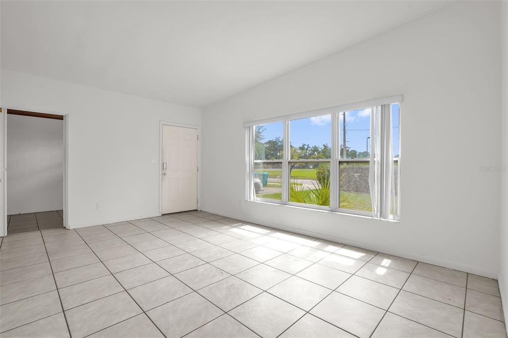 A bright, empty room features white walls, large windows, and light-colored square floor tiles — 417 N TAMPA AVENUE, ORLANDO, FL