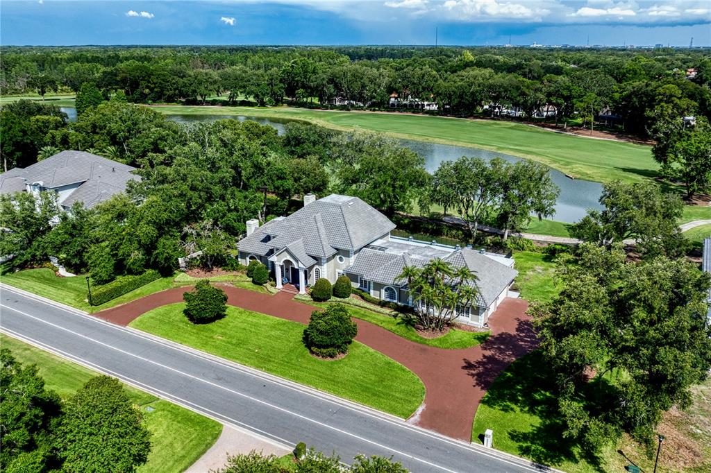 An aerial view shows a house with a gray roof and red driveway near water — 16601 AVILA BOULEVARD, TAMPA, FL