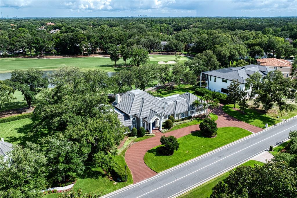 An aerial view shows a house with a gray roof, brick driveway, and golf course — 16601 AVILA BOULEVARD, TAMPA, FL