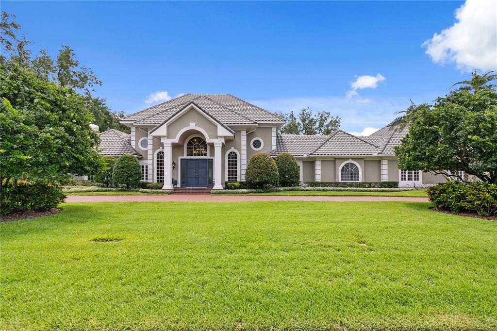 A single-story house with a tiled roof, arched entryway, and a large front lawn — 16601 AVILA BOULEVARD, TAMPA, FL