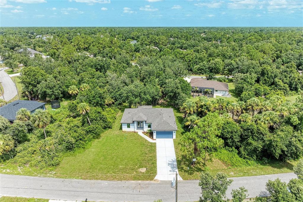 An aerial view shows a single-story house with a driveway surrounded by dense green trees — 3652 KACHER ROAD, NORTH PORT, FL