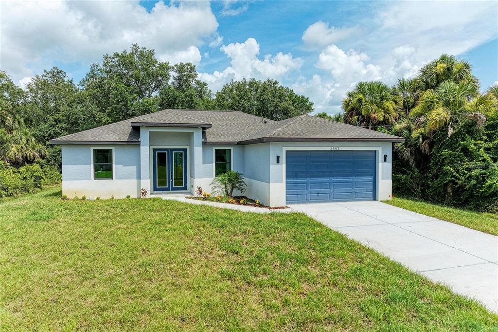 A single-story house with a blue garage door and double front doors sits on a lawn — 3652 KACHER ROAD, NORTH PORT, FL