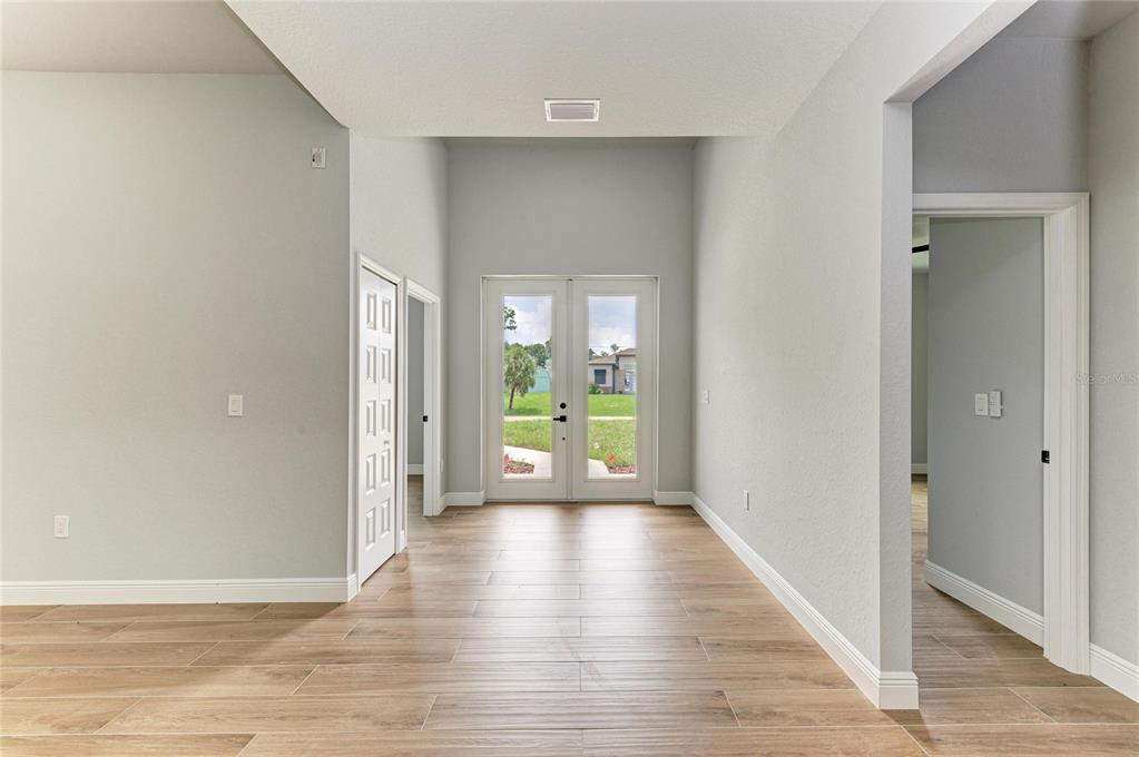 An entryway with light wood-look tile flooring, white walls, and double glass doors leading outside — 3652 KACHER ROAD, NORTH PORT, FL