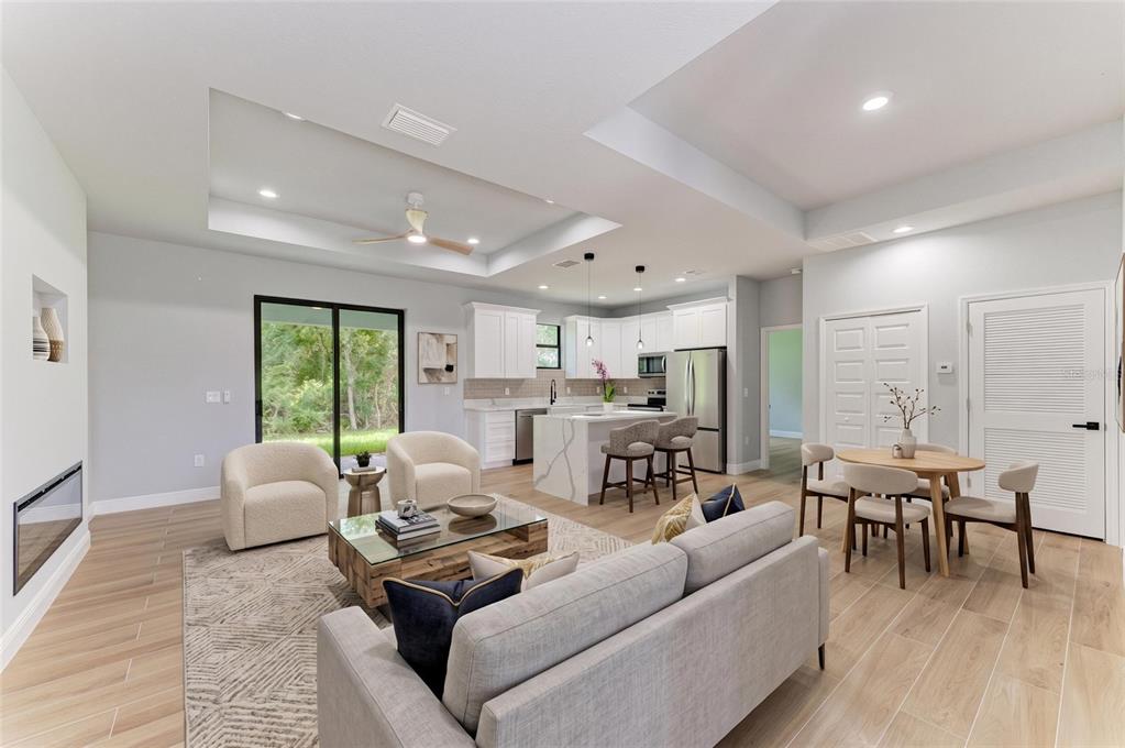 An open-concept living room and kitchen featuring light wood-look tile floors and white cabinetry — 3652 KACHER ROAD, NORTH PORT, FL