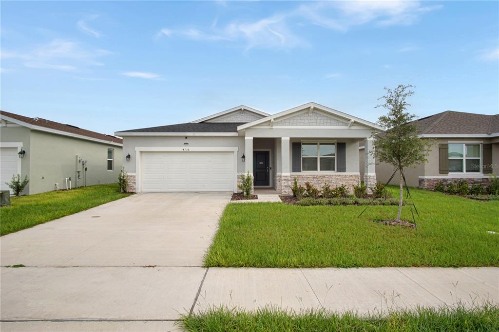 A single-story suburban house with a two-car garage, stone accents, and a front porch — 4136 LAVENDER COURT, LAKE HAMILTON, FL