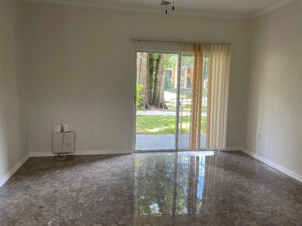 A living room with tile flooring, a sliding glass door, and a wall-mounted heater — 5602 PINNACLE HEIGHTS CIRCLE UNIT 111, TAMPA, FL