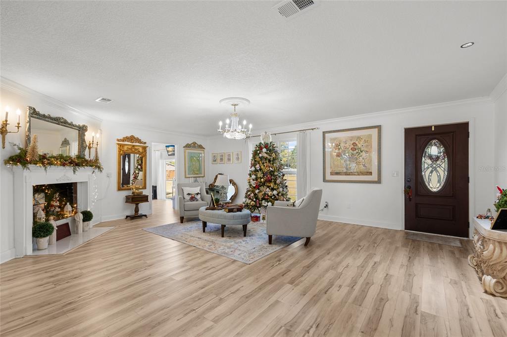A living room with light wood floors, a fireplace, a Christmas tree, and a front door — 172 SW BRADSHAW GLEN, LAKE CITY, FL