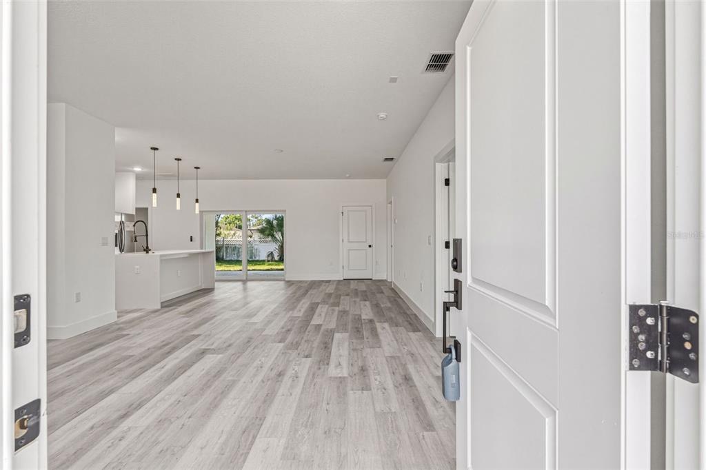 A view from an open doorway into a bright living area with wood-look flooring — 2315 MISTLETO LANE, NORTH PORT, FL
