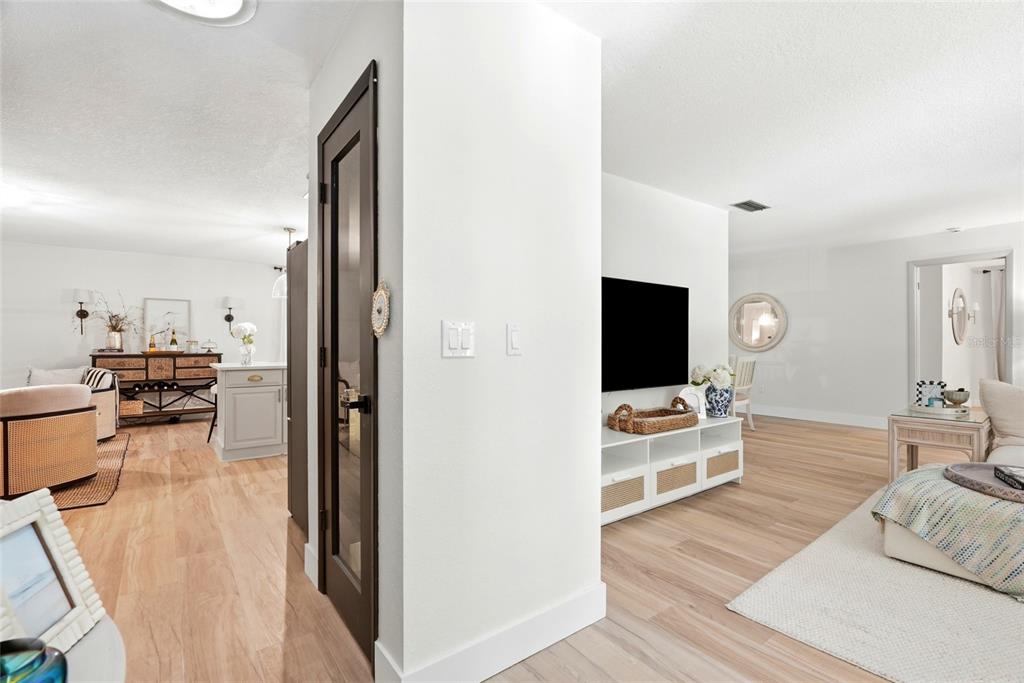 A bright living room and kitchen area feature light wood flooring and white walls — 8 CLEARVIEW DRIVE, SAFETY HARBOR, FL