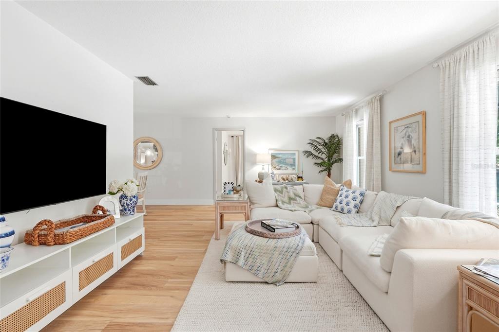 A living room features a white sectional sofa, a television, and light wood flooring — 8 CLEARVIEW DRIVE, SAFETY HARBOR, FL