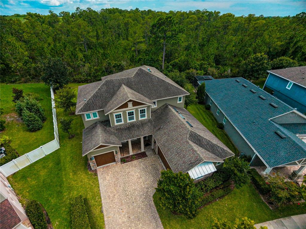 An aerial view shows a two-story house with a paved driveway and a wooded backyard — 9240 BRADLEIGH DRIVE, WINTER GARDEN, FL