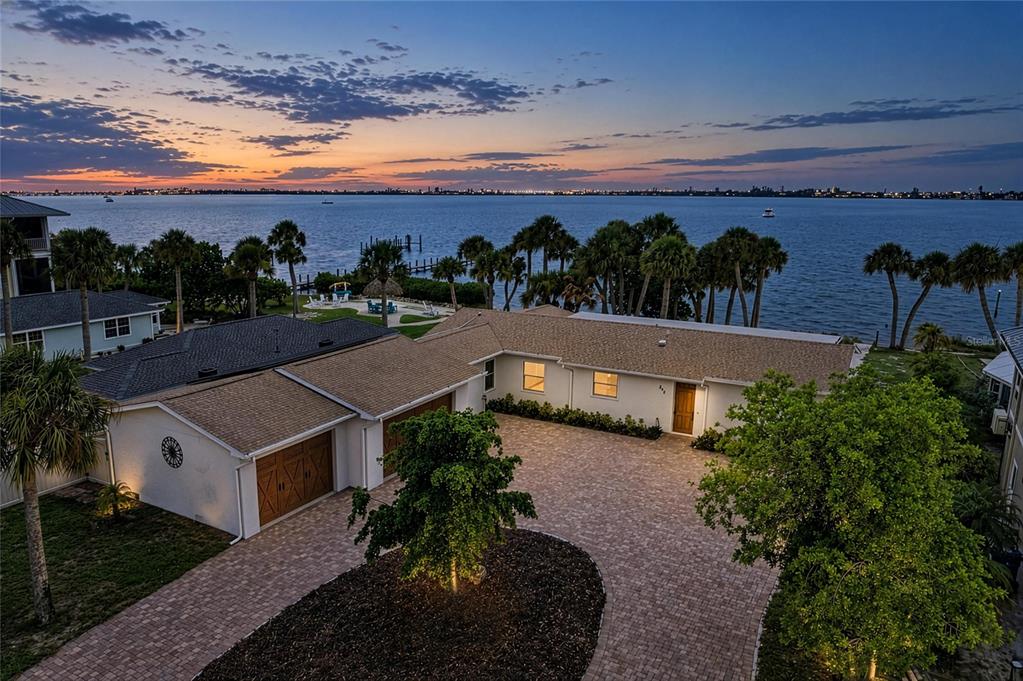An aerial view of a waterfront house with a paved driveway and a sunset sky — 211 BAHIA VISTA DRIVE, ENGLEWOOD, FL