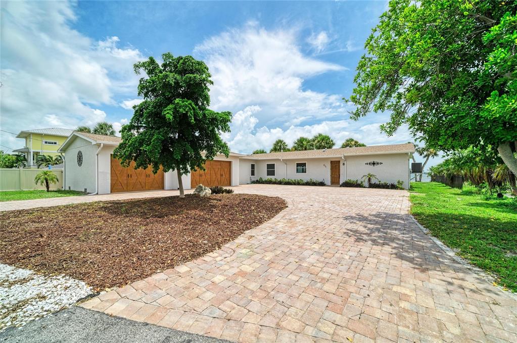A single-story house with a paved driveway, two garage doors, and a large front tree — 211 BAHIA VISTA DRIVE, ENGLEWOOD, FL