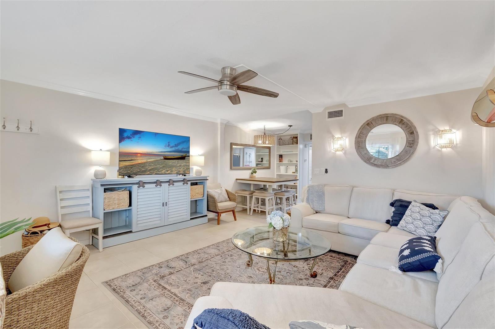 A living room with a sectional sofa, glass coffee table, TV console, and dining area — 1700 S Ocean Boulevard # 4, Delray Beach FL 33483, DELRAY BEACH, FL