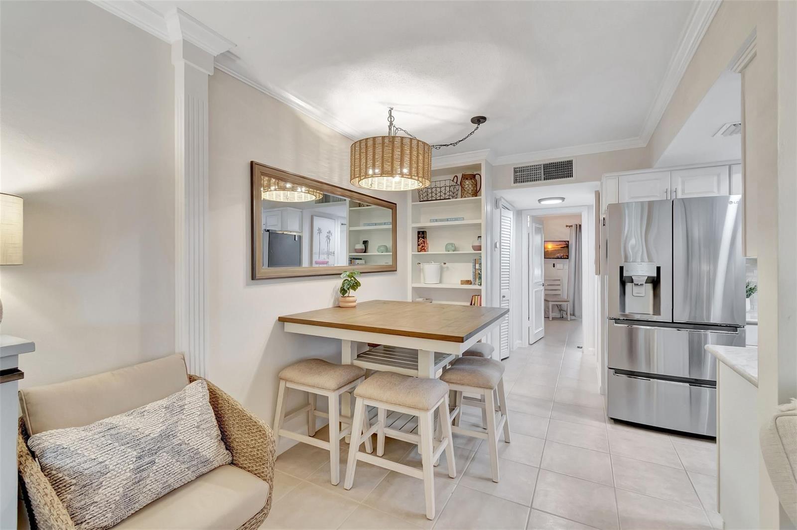 A dining area features a square wooden table, four stools, a mirror, and built-in shelving — 1700 S Ocean Boulevard # 4, Delray Beach FL 33483, DELRAY BEACH, FL