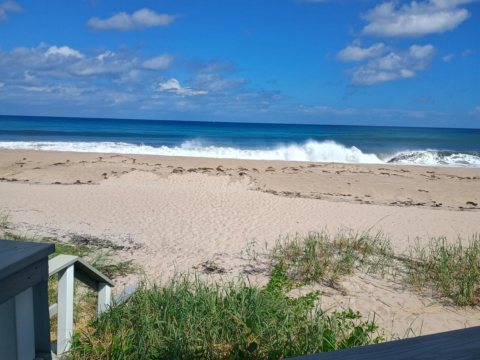 A sandy beach with ocean waves, seen from a wooden deck with stairs — 5505 N Ocean Boulevard # 110, Ocean Ridge FL 33435, OCEAN RIDGE, FL
