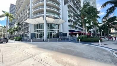 A low-angle exterior view of a modern multi-story apartment building with a white canopy entrance — 690 SW 1st Ct # 1908, Miami FL 33130, MIAMI, FL