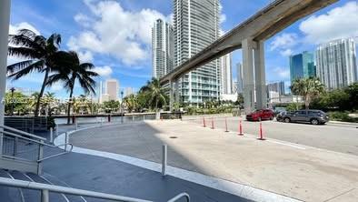 An outdoor paved area with palm trees, a concrete overpass, and city skyscrapers in the background — 690 SW 1st Ct # 1908, Miami FL 33130, MIAMI, FL