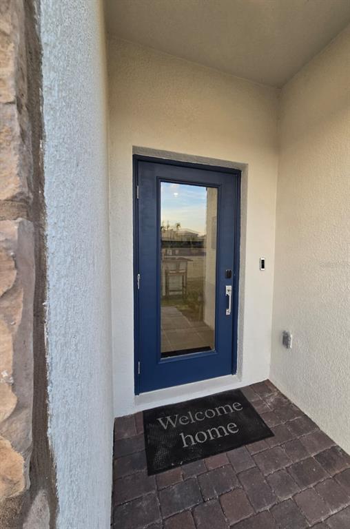 A blue front door with a glass panel sits on a paved porch — 4244 ST THOMAS WAY, KISSIMMEE, FL