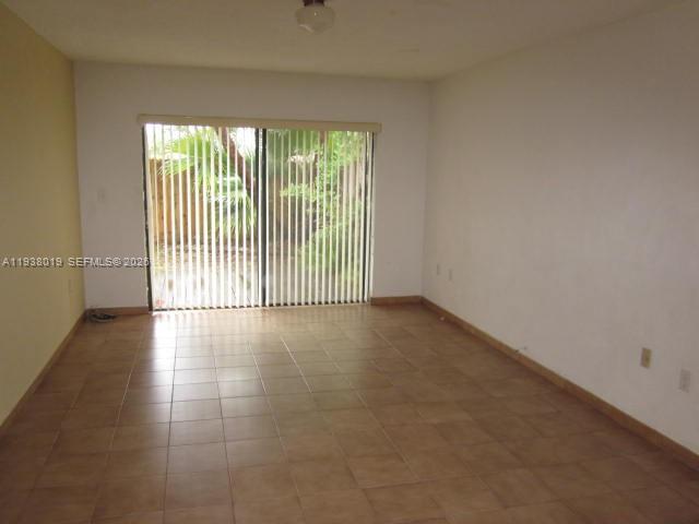 An empty room features beige tile flooring, white walls, and a sliding glass door — 13224 SW 10 TE # 0, Miami FL 33184, MIAMI, FL