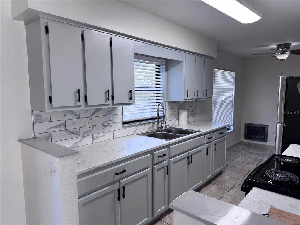 A kitchen features gray cabinets, white marble-patterned countertops, and a matching subway tile backsplash — 15144 SW 27TH COURT, OCALA, FL