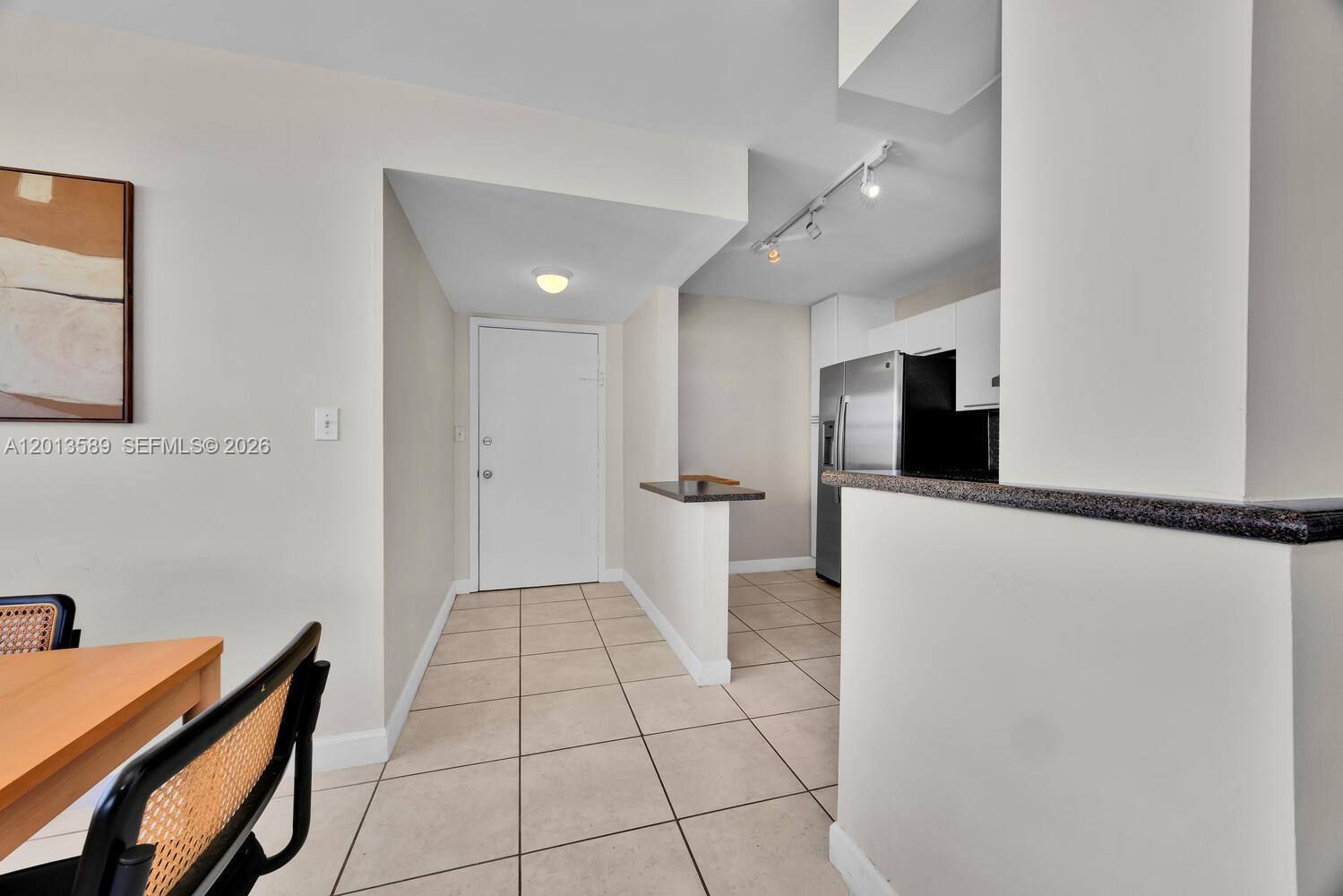 A tiled entryway leads to a kitchen with stainless steel appliances and a breakfast bar — 2016 Bay Dr # 604, Miami Beach FL 33141, MIAMI BEACH, FL