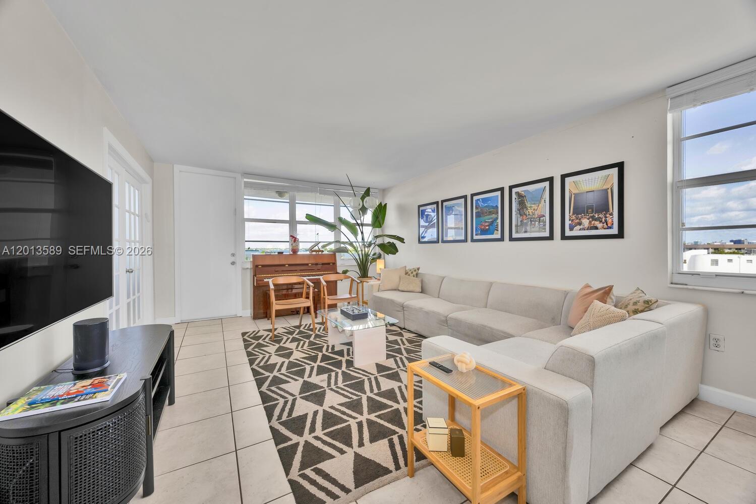 A living room features a large sectional sofa, a geometric rug, and a piano — 2016 Bay Dr # 604, Miami Beach FL 33141, MIAMI BEACH, FL