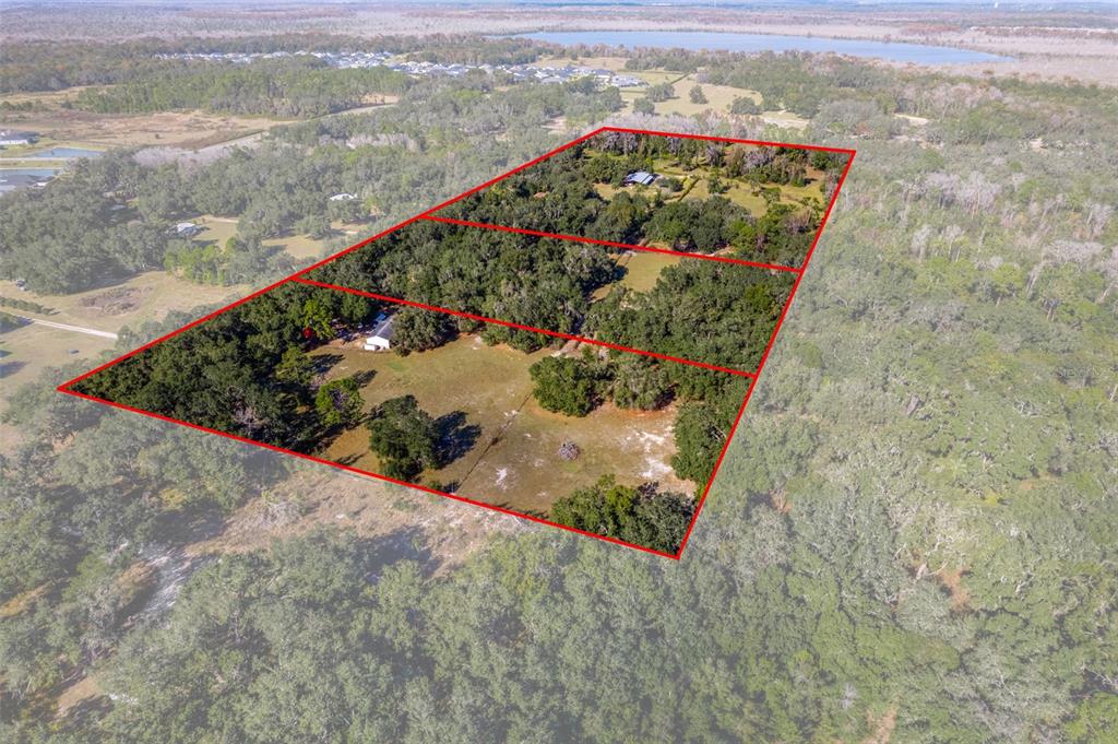 An aerial view shows three adjacent rectangular parcels of land with trees and structures — 27910 & 27750 DEBBIE ROAD, OKAHUMPKA, FL