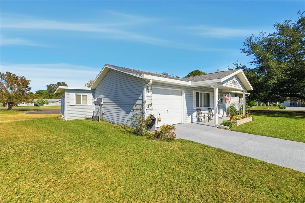 A light blue single-story house with a white garage door and a covered front porch — 10599 SE 178TH STREET, SUMMERFIELD, FL
