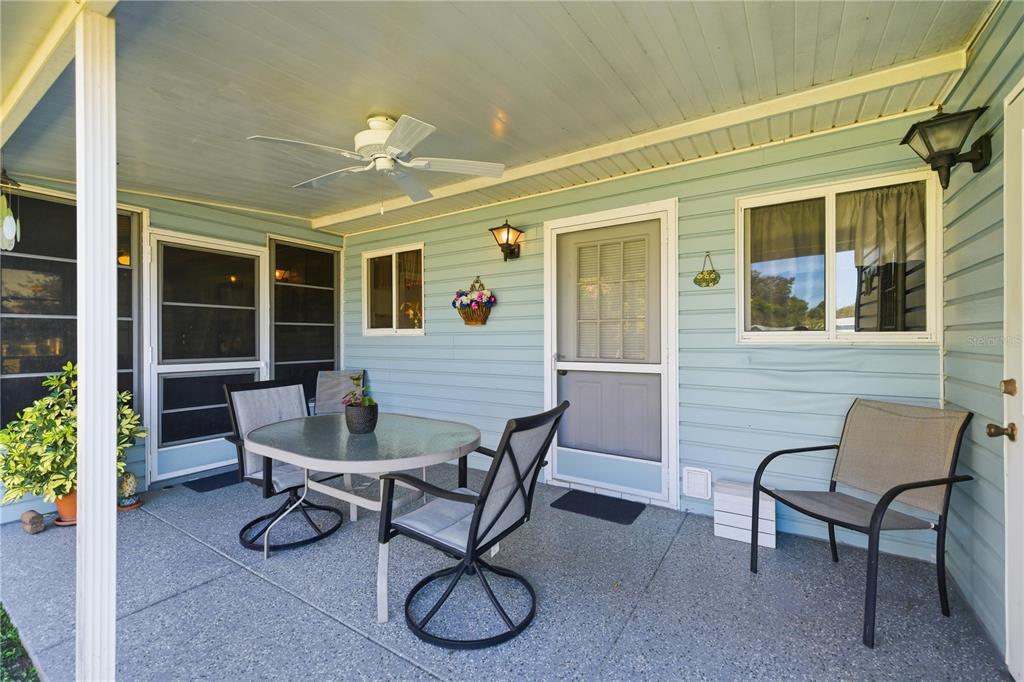 A covered patio features light blue siding, a ceiling fan, and outdoor furniture on concrete — 10599 SE 178TH STREET, SUMMERFIELD, FL
