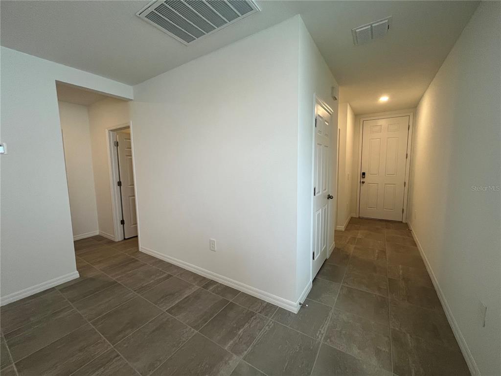 An interior view shows a tiled hallway leading to a white front door — 4973 KAIA AVENUE, WINTER HAVEN, FL