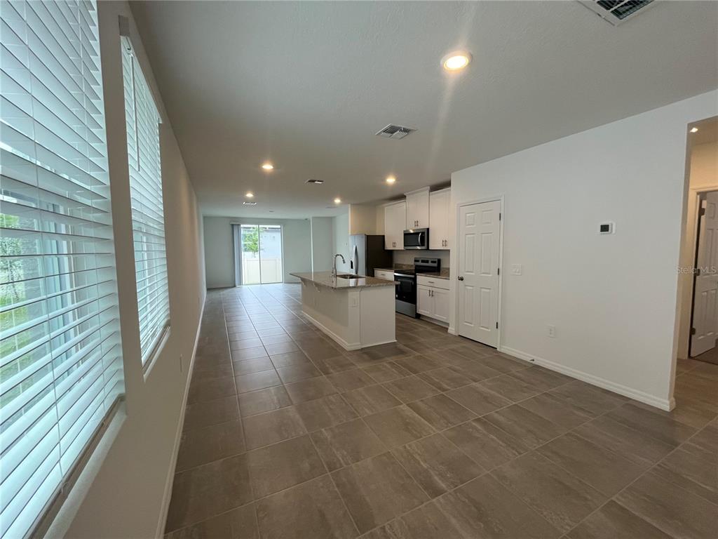 An open-concept kitchen features a granite island, white cabinetry, and tile flooring — 4973 KAIA AVENUE, WINTER HAVEN, FL