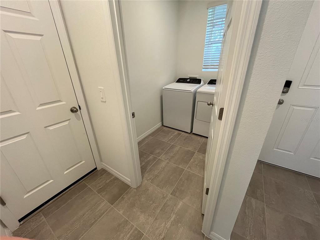 A laundry room with a white washer and dryer, tile flooring, and a window — 4973 KAIA AVENUE, WINTER HAVEN, FL