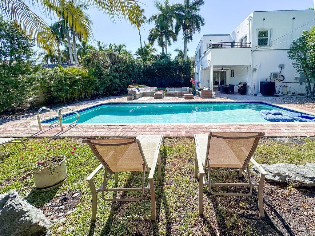A backyard features a swimming pool, patio furniture, and two lounge chairs on grass — 1255 Jackson St, Hollywood FL 33019, HOLLYWOOD, FL