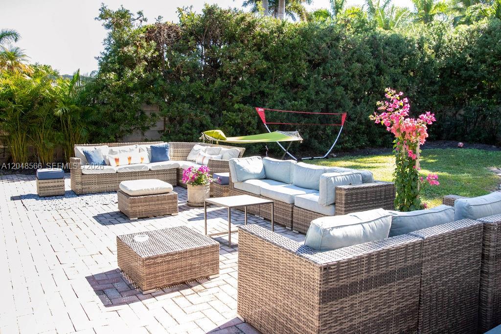 A patio features wicker outdoor furniture with light blue cushions on a paved surface — 1255 Jackson St, Hollywood FL 33019, HOLLYWOOD, FL
