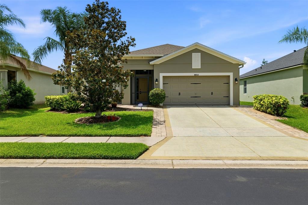 A single-story house with a beige exterior, a two-car garage, and a landscaped front yard — 8854 39TH STREET CIRCLE E, PARRISH, FL