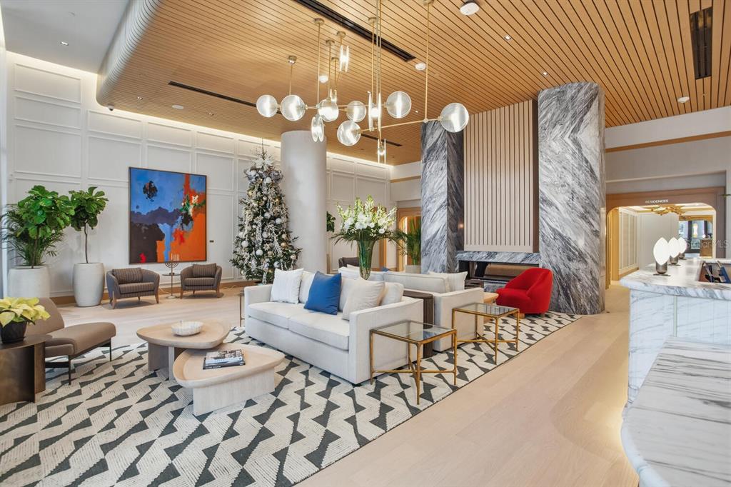 A modern lobby features a marble fireplace, a geometric rug, and a large Christmas tree — 3015 S YSABELLA AVENUE UNIT 1202, TAMPA, FL