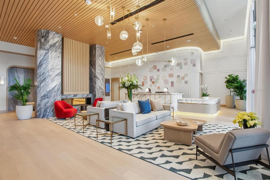 A modern lobby features a marble fireplace, seating area, and a large geometric patterned rug — 3015 S YSABELLA AVENUE UNIT 1202, TAMPA, FL