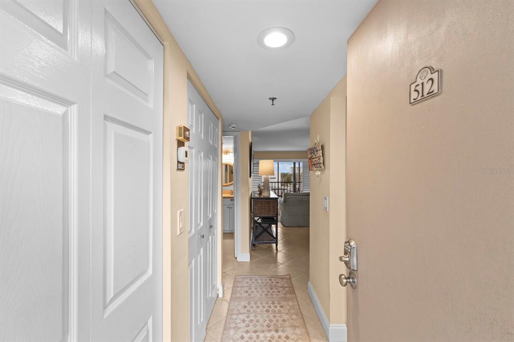 An interior hallway leads from an entryway door toward a living area with tile flooring — 1001 BENJAMIN FRANKLIN DRIVE UNIT 512, SARASOTA, FL
