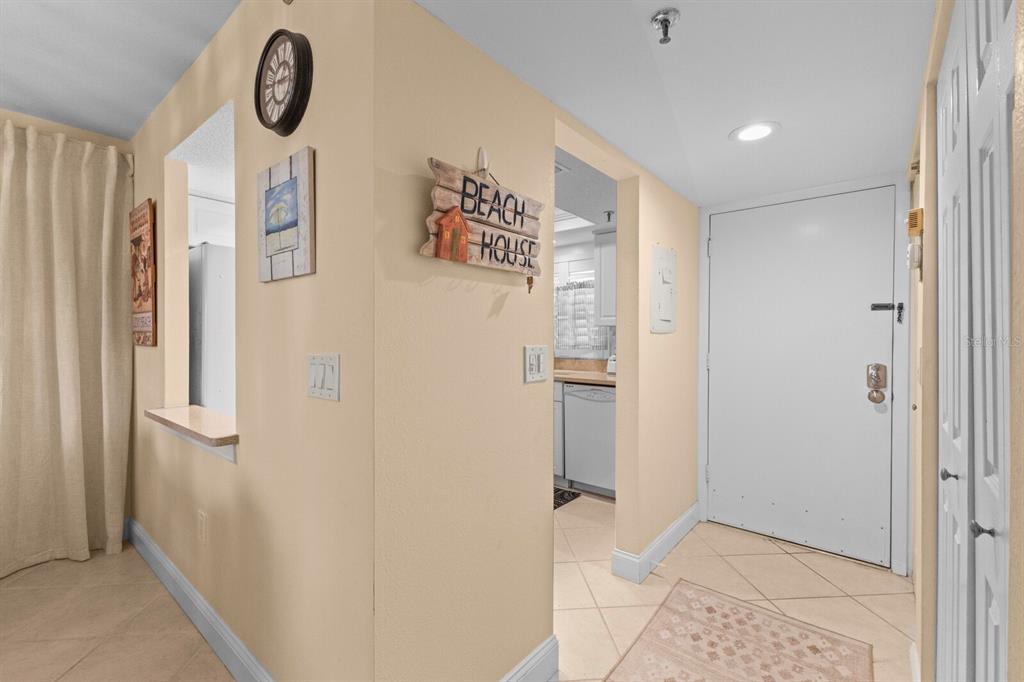 An entryway with tile floors leads to a kitchen area featuring a beach house sign — 1001 BENJAMIN FRANKLIN DRIVE UNIT 512, SARASOTA, FL